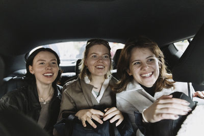 Excited female friends traveling in car on vacation