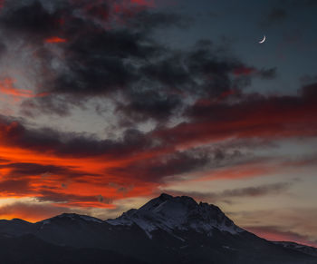 Scenic view of mountains against dramatic sky during sunset