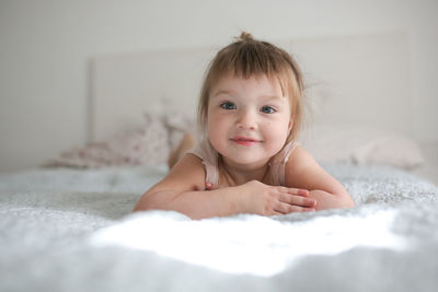 Happy funny girl toddler lifestyle with a smile lying on the bed, close-up, 
