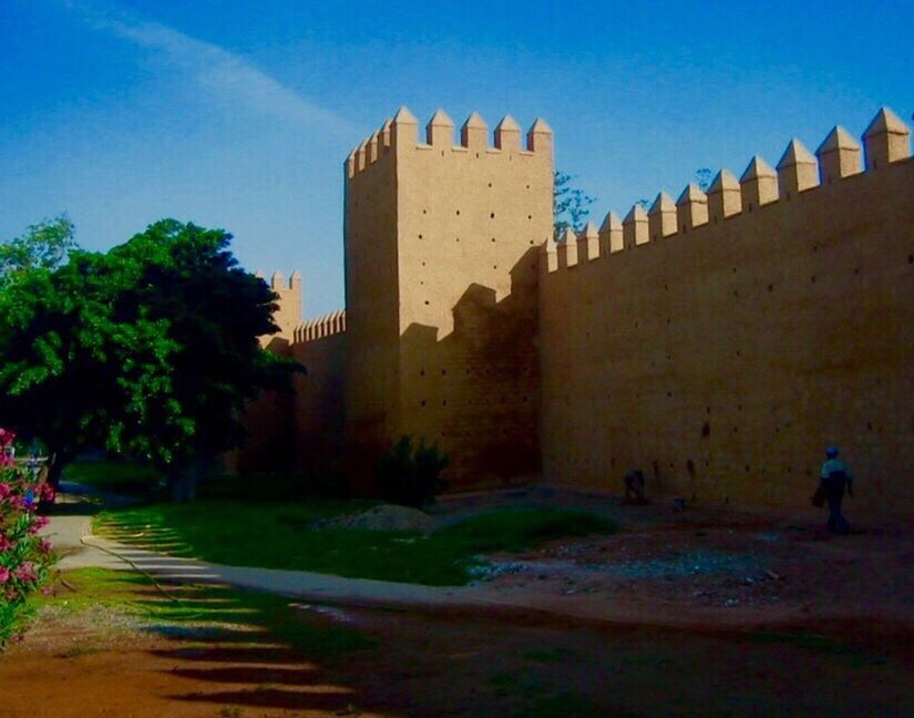 architecture, built structure, building exterior, sky, history, clear sky, men, walking, the way forward, blue, tree, building, house, wall - building feature, shadow, castle, lifestyles, residential structure