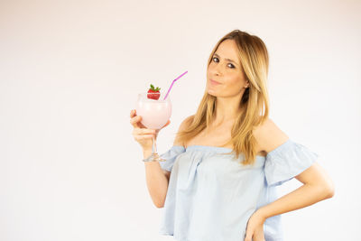 Young woman holding drink against white background