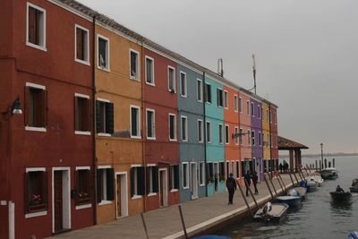 Buildings by sea against clear sky