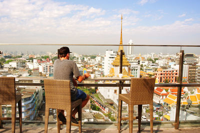 Rear view of man sitting on table in city