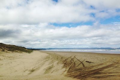 Scenic view of beach against cloudy sky