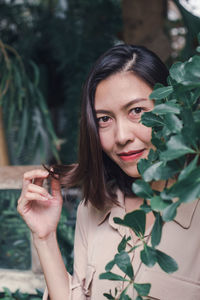 Portrait of a beautiful young woman holding plant