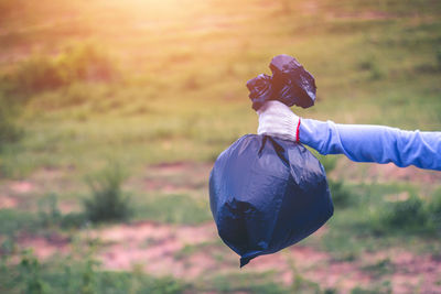 Close-up of person holding garbage bag on plants