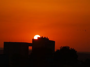 Low angle view of silhouette building against orange sky