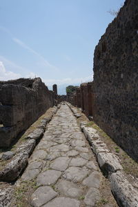 Footpath by wall against sky