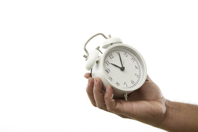 Close-up of hand holding clock against white background
