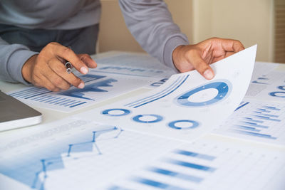 Midsection of man holding paper on table