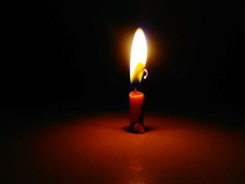 Close-up of illuminated candle in darkroom