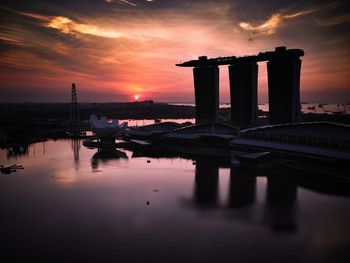 Marina bay sands by sea against sky during sunset in city