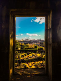 Buildings against sky seen through window