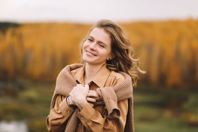 A pretty girl enjoys solitude drinks coffee walks in the autumn forest in nature in fall