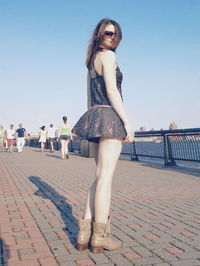 Portrait of young woman standing against clear sky
