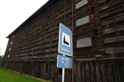 Low angle view of road sign by building against sky