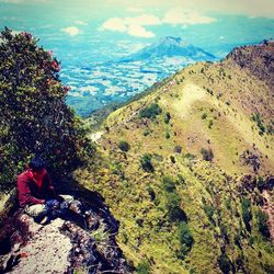 High angle view of woman sitting on rock against sky