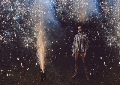 Man standing amidst firework display at night