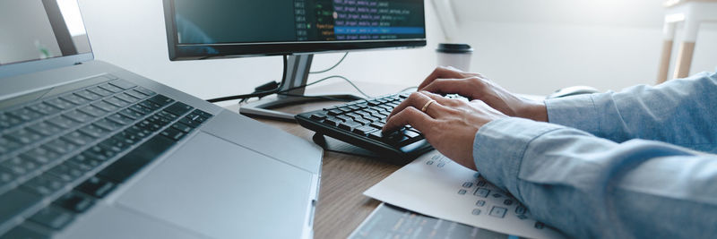 Cropped hand of businessman using computer on table