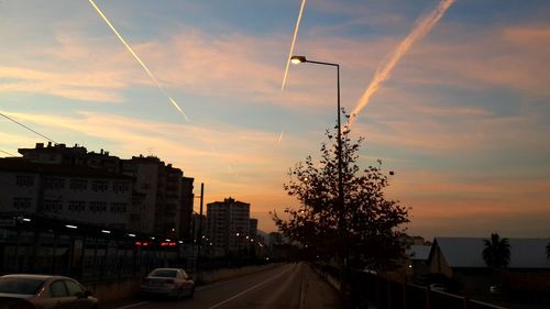 Cars on road against sky at sunset