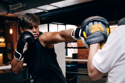 Young man boxing while standing at gym