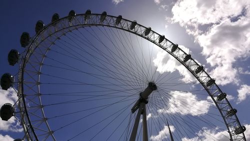 Low angle view of ferris wheel against cloudy sky