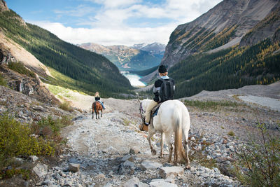 Rear view of people riding horses on mountains