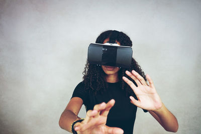 Woman wearing virtual reality simulator while gesturing against wall