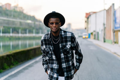 Portrait of young man standing on road in city