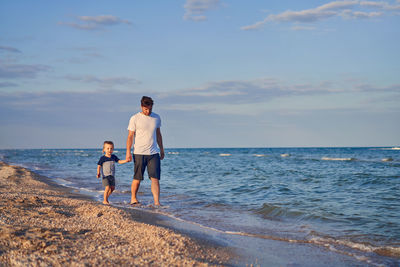 Full length of men on beach against sky