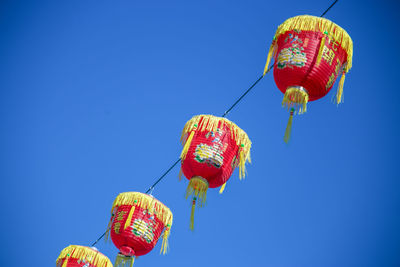 Low angle view of illuminated lanterns against clear blue sky