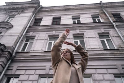 Low angle view of woman walking by building in city