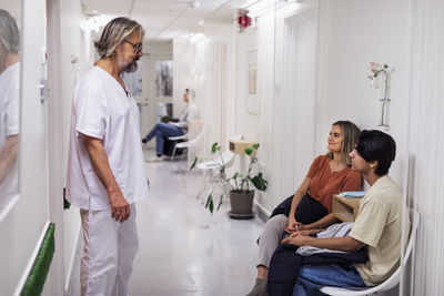 Doctor talking to patients in hospital corridor