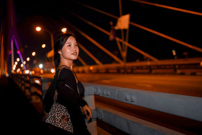 Portrait of young woman standing in city at night