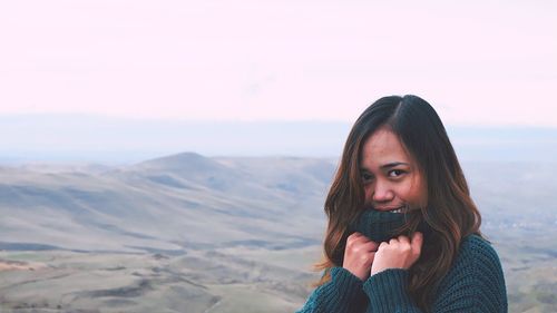 Portrait of smiling young woman standing against sky