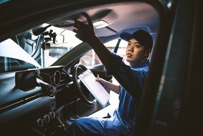 Mechanic man checking up in car for repairing