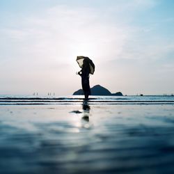 Woman standing in sea against sky on sunny day