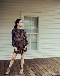 Full length portrait of woman standing against wall