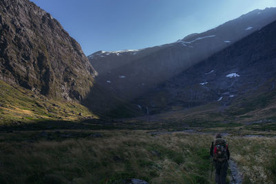 Rear view of woman walking on field against sky