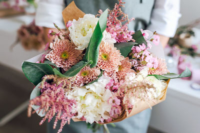 An employee of a flower boutique holds a freshly picked bouquet.