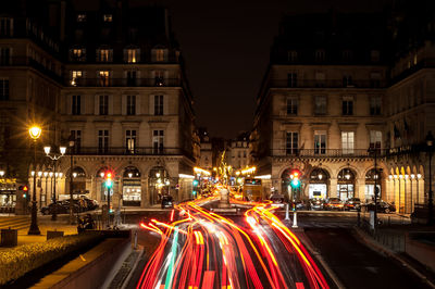 Light trails on road amidst buildings in city at night
