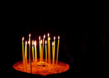 Close-up of illuminated candles against black background