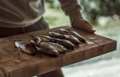 Midsection of man holding sea food on cutting board