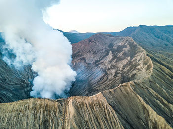 Smoke emitting from volcanic mountain against sky