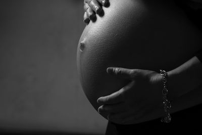 Midsection of woman touching face against gray background