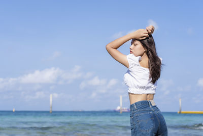 Rear view of woman standing at beach against sky