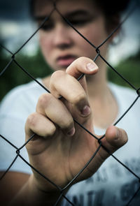 Close-up of girl seen through chainlink fence