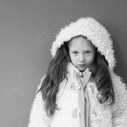 Portrait of girl in fluffy jacket standing by wall