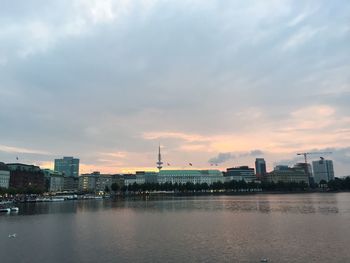 City at waterfront against cloudy sky