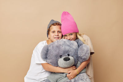 Portrait of cute girl with stuffed toy against yellow background